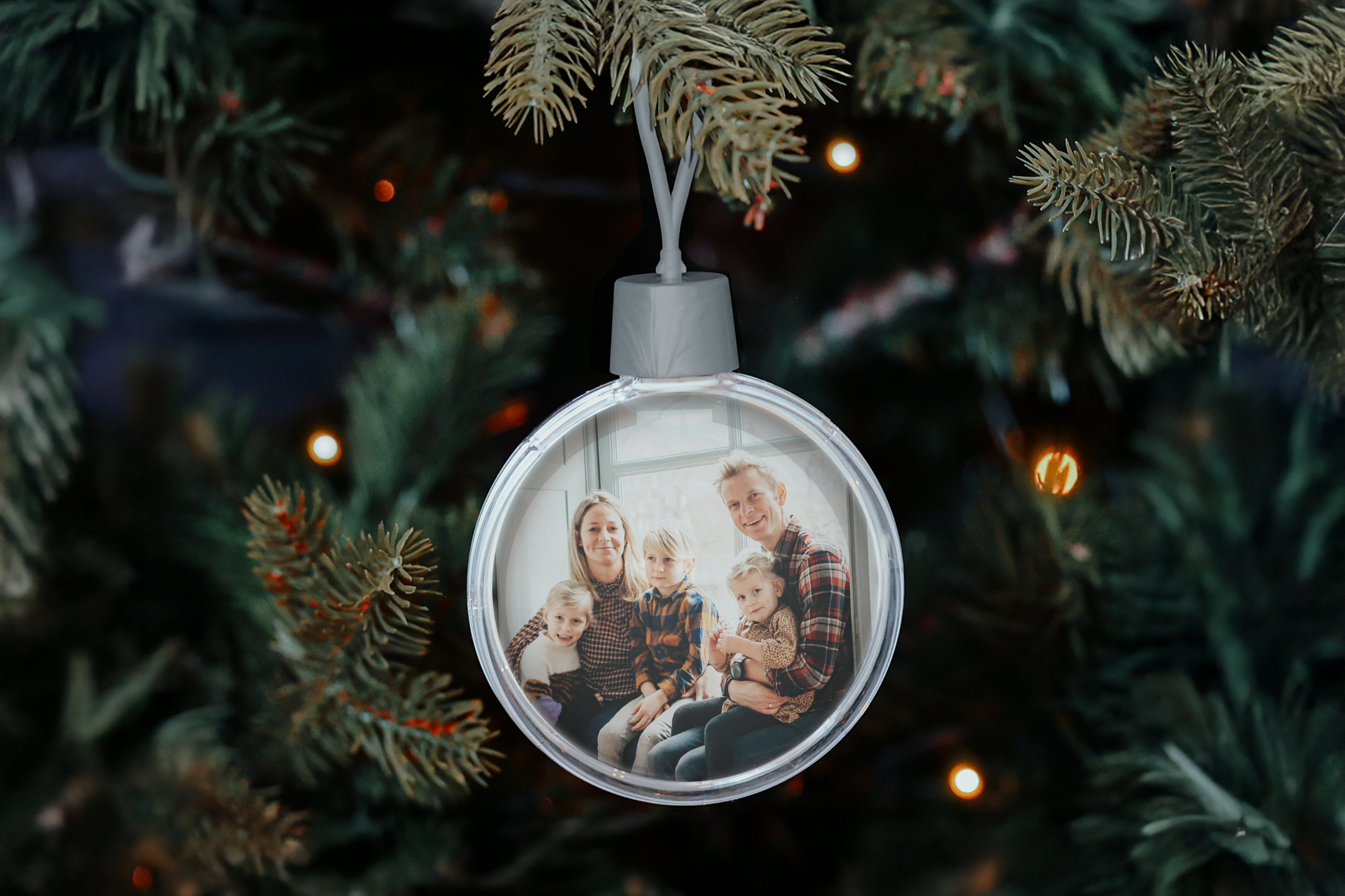 boule de noel personnalisée avec photo de famille suspendue à un sapin, décor festif, personnalisée avec image imprégnée dans la boule