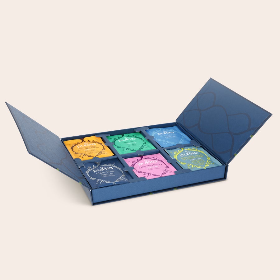 Té Pukka personalizado Juego de regalo de té Pukka personalizado con seis variedades, con una caja azul abierta mostrando los sobres de té de colores.