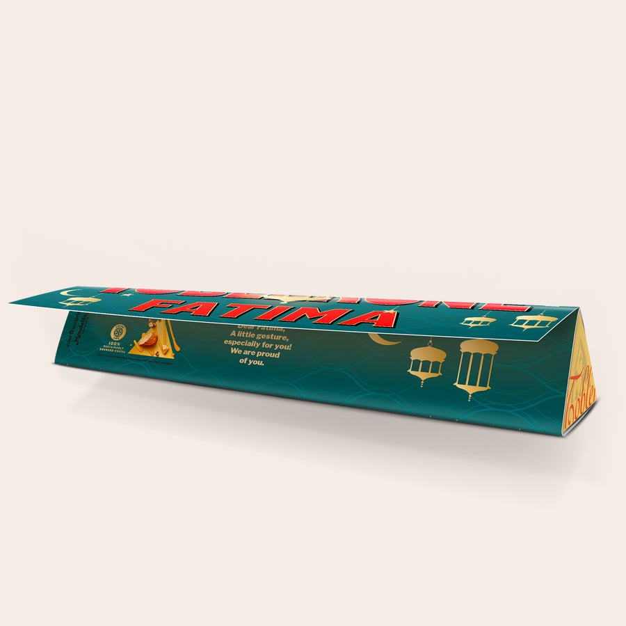 Baton de ciocolată Toblerone personalizat - Ramadan Toblerone personalizat pentru Ramadan, cu ambalaj verde închis imprimat cu numele "Fatima" și un mesaj personal, decorat cu felinare aurii.