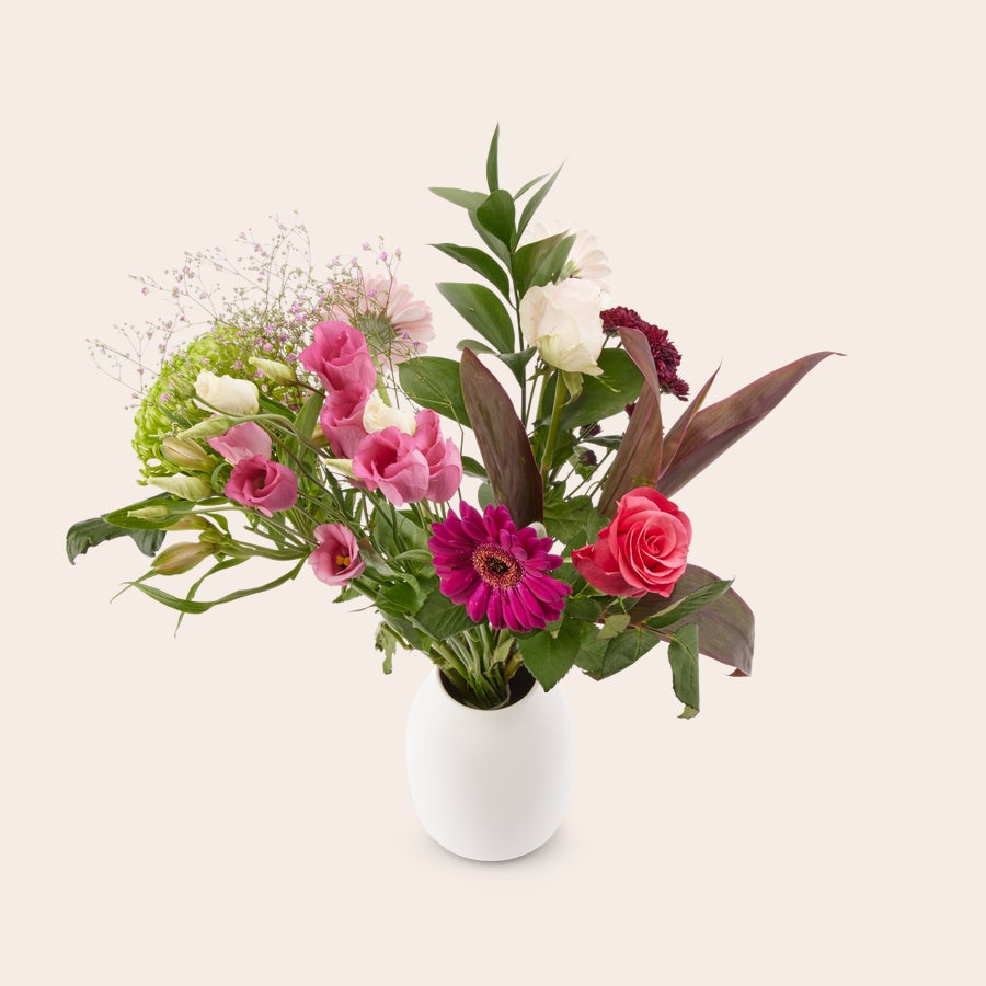 Bloemen - Roze plukboeket Een prachtig roze plukboeket met diverse bloemen en frisgroen blad in een witte vaas, inclusief gratis cadeaukaartje voor een persoonlijke boodschap.