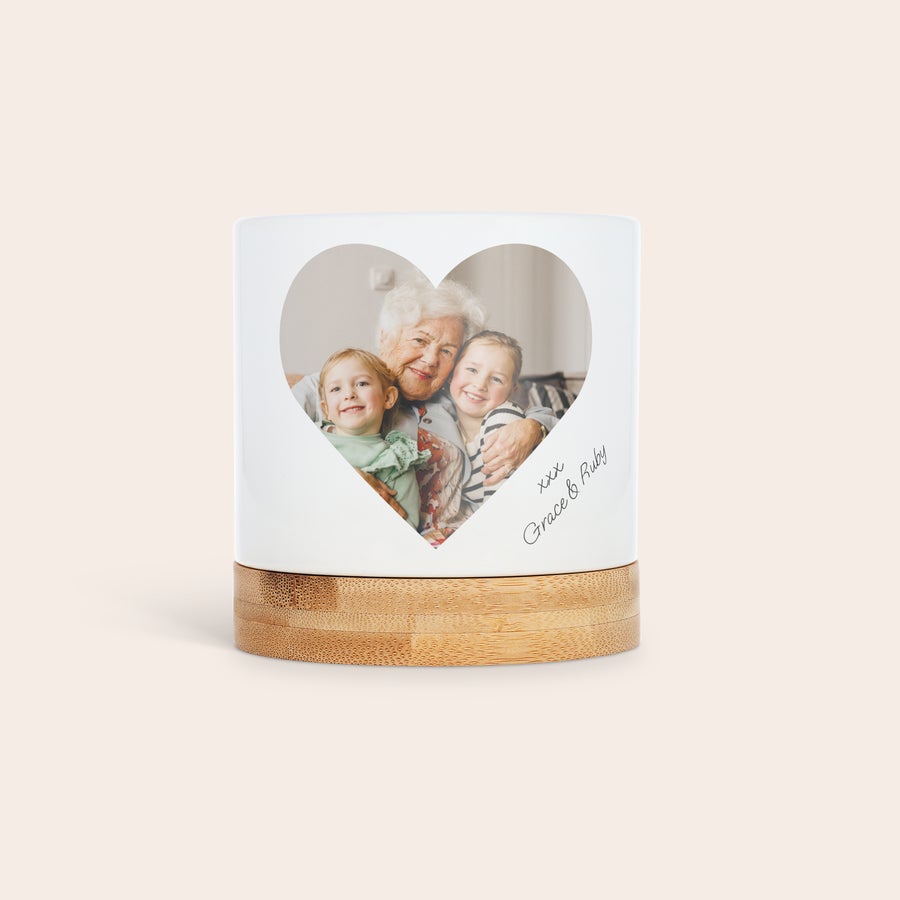 Personaliziran cvetlični lonec Beli keramični cvetlični lonec z bambusovim podstavkom in natisnjeno fotografijo srca ter osebnim sporočilom Grace & Ruby. Dajte jim zelenje z osebno noto, ki jo bodo cenili.