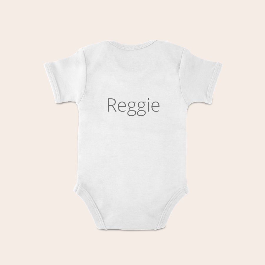 Otroška obleka Belo osebno otroško oblačilo s sivim napisom Reggie, natisnjeno z izbranim besedilom