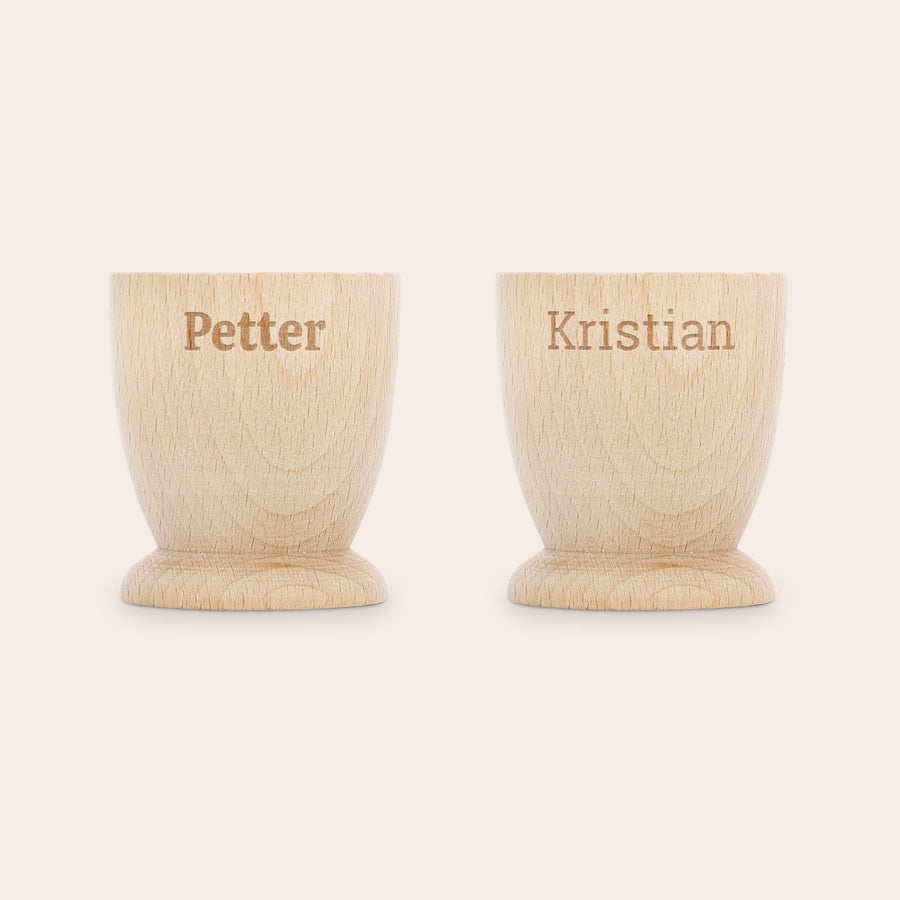 Personifierad äggkopp Två personliga äggkoppar i bokträ, en graverad med Petter och den andra med Kristian för att göra frukosten minnesvärd.