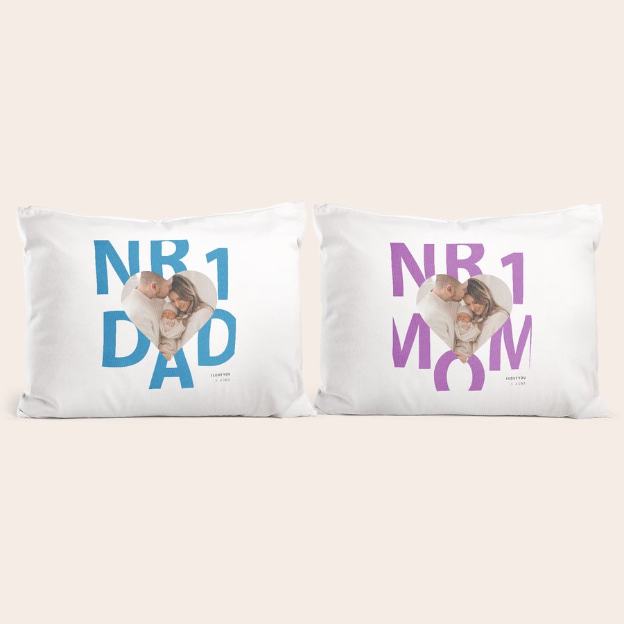 Set federe con stampa - Amore Set di federe a tema amoroso personalizzate: la federa "Nr 1 Dad" con foto di coppia e neonato stampata a cuore, e la federa "Nr 1 Mom" con foto di coppia e neonato stampata a cuore.