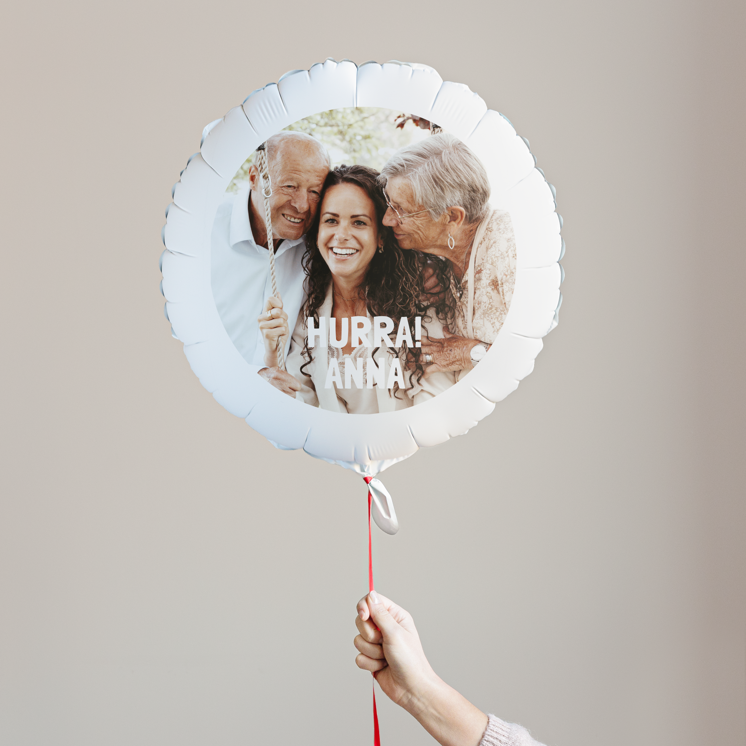 Personalisierter Fotoballon mit Familiendruck und dem Text Hurra Anna, gehalten an einem roten Band