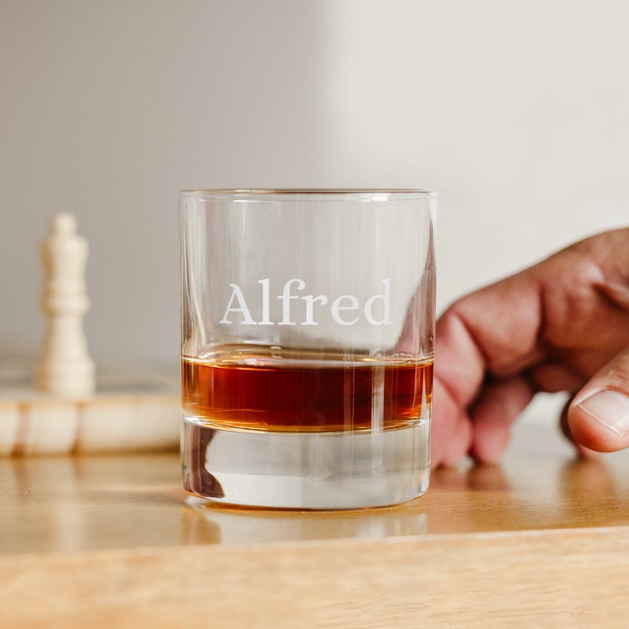 Tumbler Glas mit Gravur Der Tumbler aus Glas ist mit Whisky gefüllt, der Name "Alfred" ist eingraviert, eine beliebte Glasform für deinen Whisky
