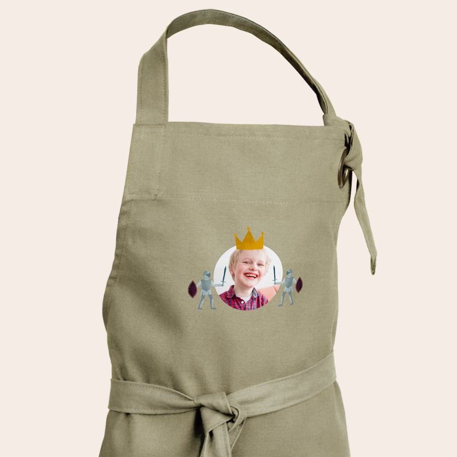 Delantal infantil personalizado Delantal para niños en tono verde arena, personalizado con la foto de un niño sonriendo, diseño de corona y caballeros.