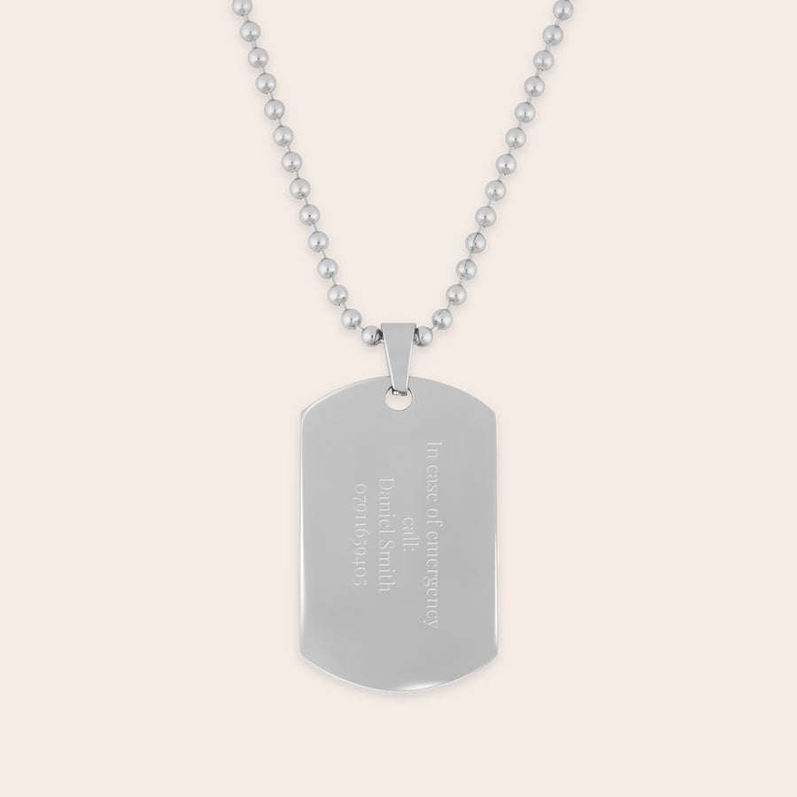 Dog tag pendant with necklace Silver name tag engraved with text, "In case of emergency call: Daniel Smith 07011659405," on a ball chain.