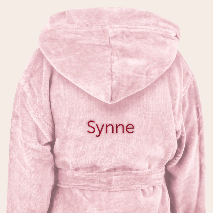 Badekåpe - barn En myk, rosa barnebadekåpe med hette og beltet brodert med navnet "Synne" i rødt, perfekt for å overraske barna.