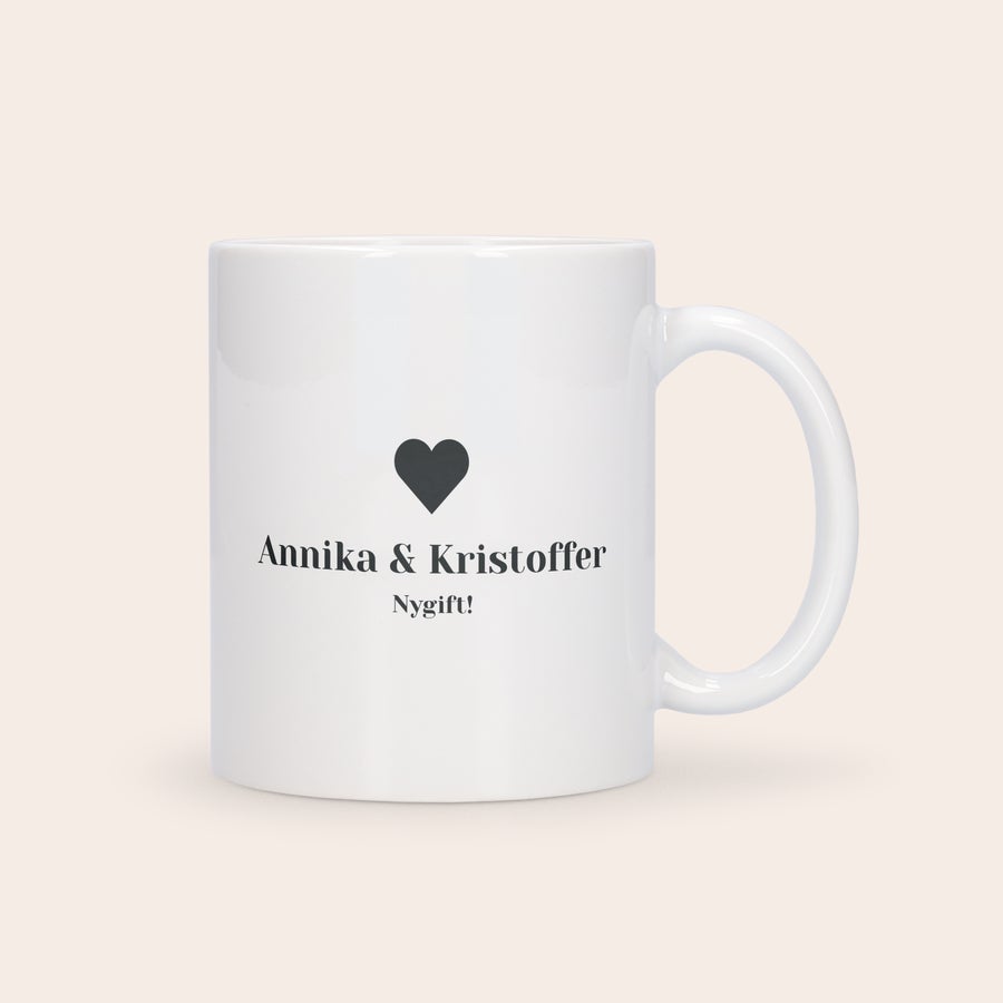 Personaliseret kærlighedskrus – Særudgave Hvidt kærlighedskrus personaliseret med navnene "Annika & Kristoffer" og teksten "Nygift!" samt et sort hjerte.