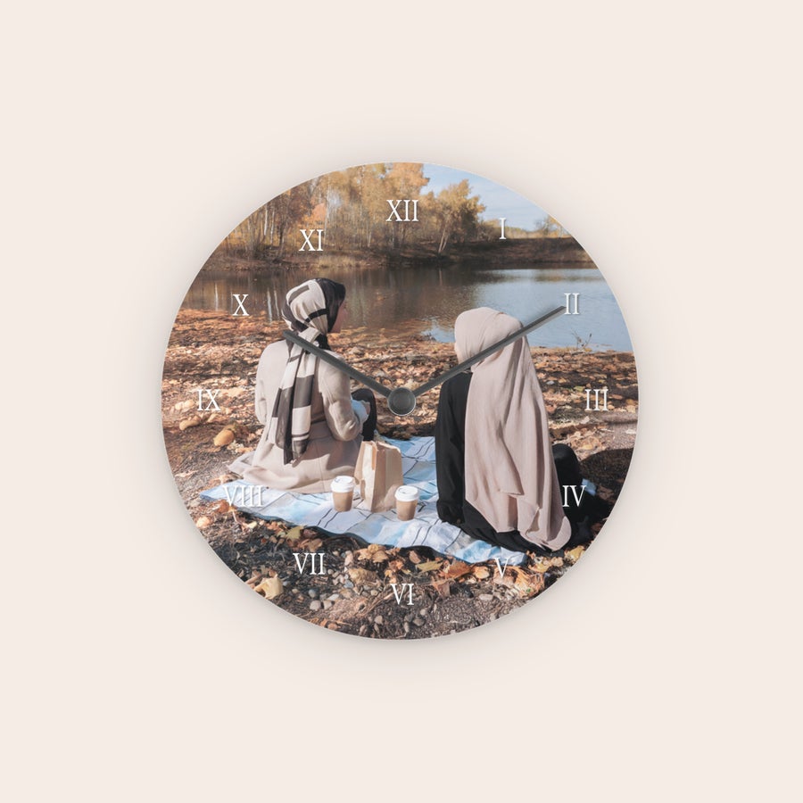 Personalised wall clock A personalized clock printed with a photo of two women having a picnic by a lake