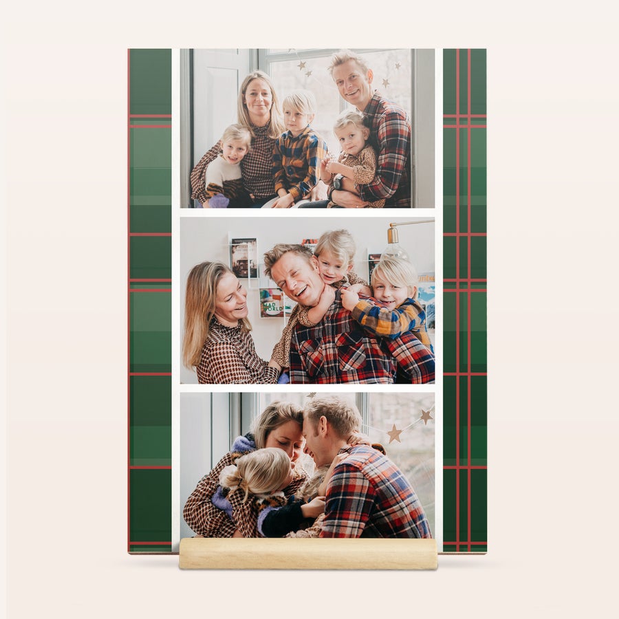 Felicitare de Crăciun foto din lemn Felicitare personală din lemn, imprimată cu trei fotografii de familie și un model cu carouri verzi și roșii, așezată pe un suport de lemn.