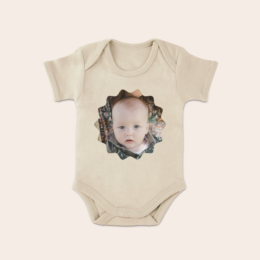 Vauvan bodysuit Yllätä uudet vanhemmat suloisella beigellä potkupuvulla, jossa on painettu kuva sinisilmän vauvan kasvoista.
