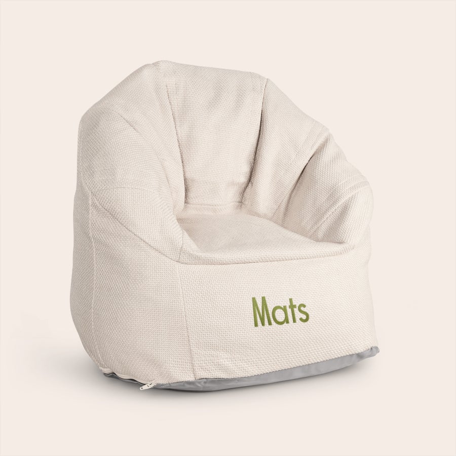 Kindersitzsack mit Namen besticken Beigefarbener Kindersitzsack bestickt mit dem grünen Namen Mats auf der Vorderseite
