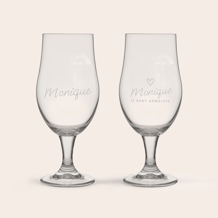 Bierglas met naam Twee glazen bierglazen met de naam Monique, een hartje en de tekst "JE BENT GEWELDIG" erop gegraveerd.