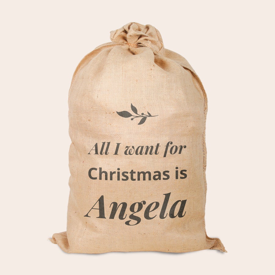 Jute kerstzak met naam bedrukt Unieke jute kerstzak bedrukt met de tekst All I want for Christmas is Angela en een takje.