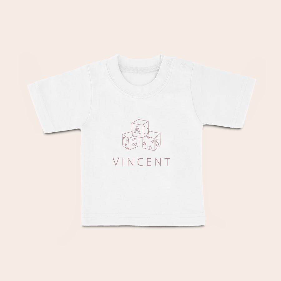 Baby shirt bedrukken Wit baby shirt bedrukt met rode speelgoedblokken, de letters A, B, C en de naam Vincent.