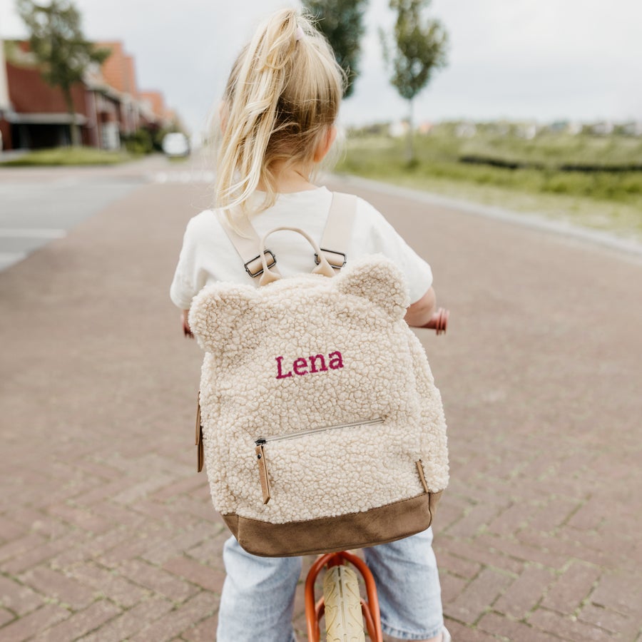 Zaino orsacchiotto personalizzato Zaino teddy personalizzato beige con orecchie, ricamato con il nome Lena, indossato da una bambina su un triciclo