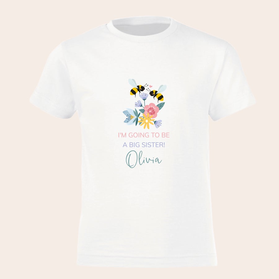 T-shirt Personalizada - Irmão/irmã mais velho/a T-shirt branca personalizada com texto "I'm going to be a big sister!" e nome Olivia com desenho de abelhas e flores