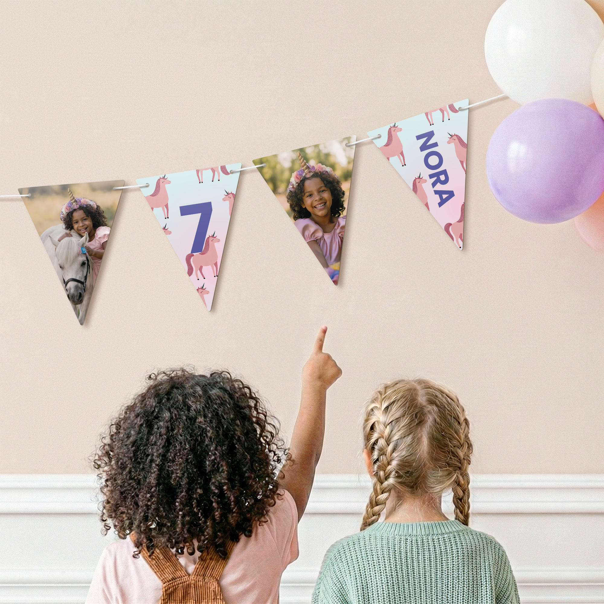 Personalised garland - Triangle - M - 10m, printed with photos of a girl and text Nora, hanging on a wall.