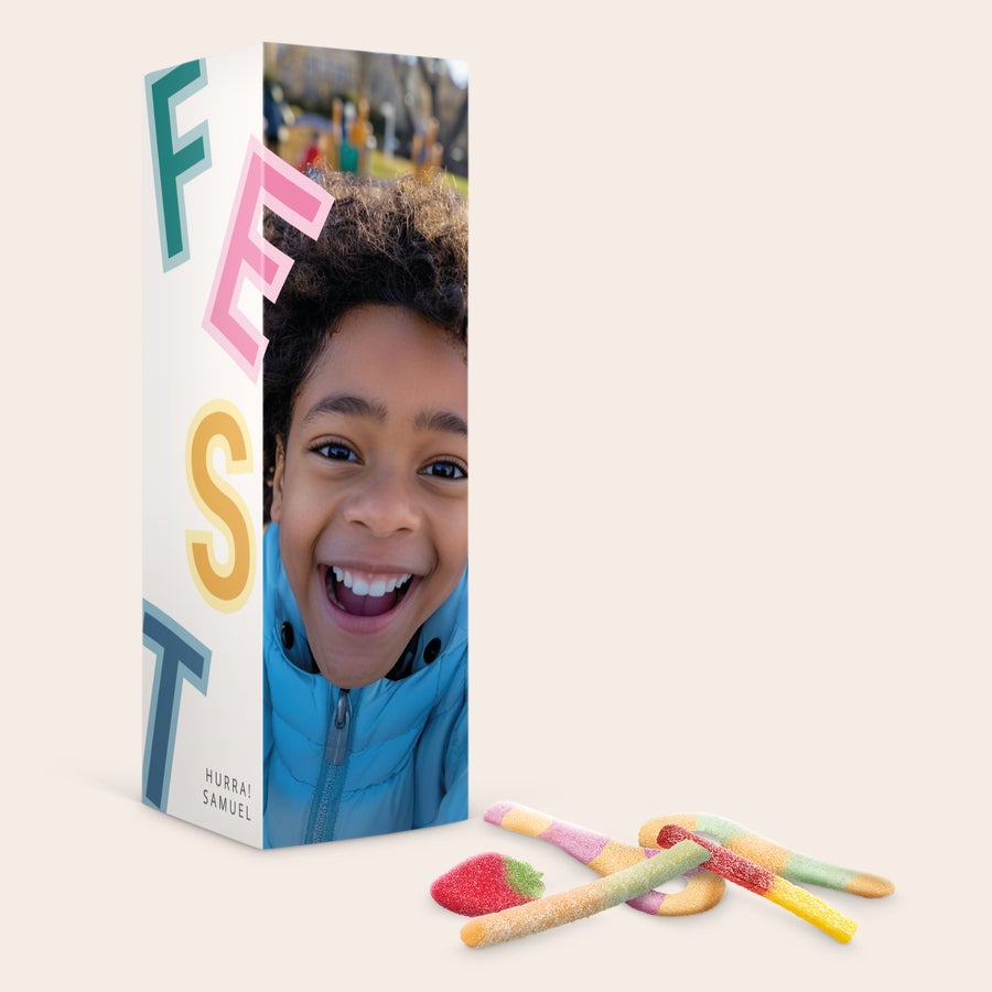 Süßigkeiten Geschenkbox - Red Band Personalisierte Süßigkeiten-Geschenkbox mit dem Foto eines lachenden Kindes und dem Text HURRA SAMUEL aufgedruckt, daneben Gummibärchen.