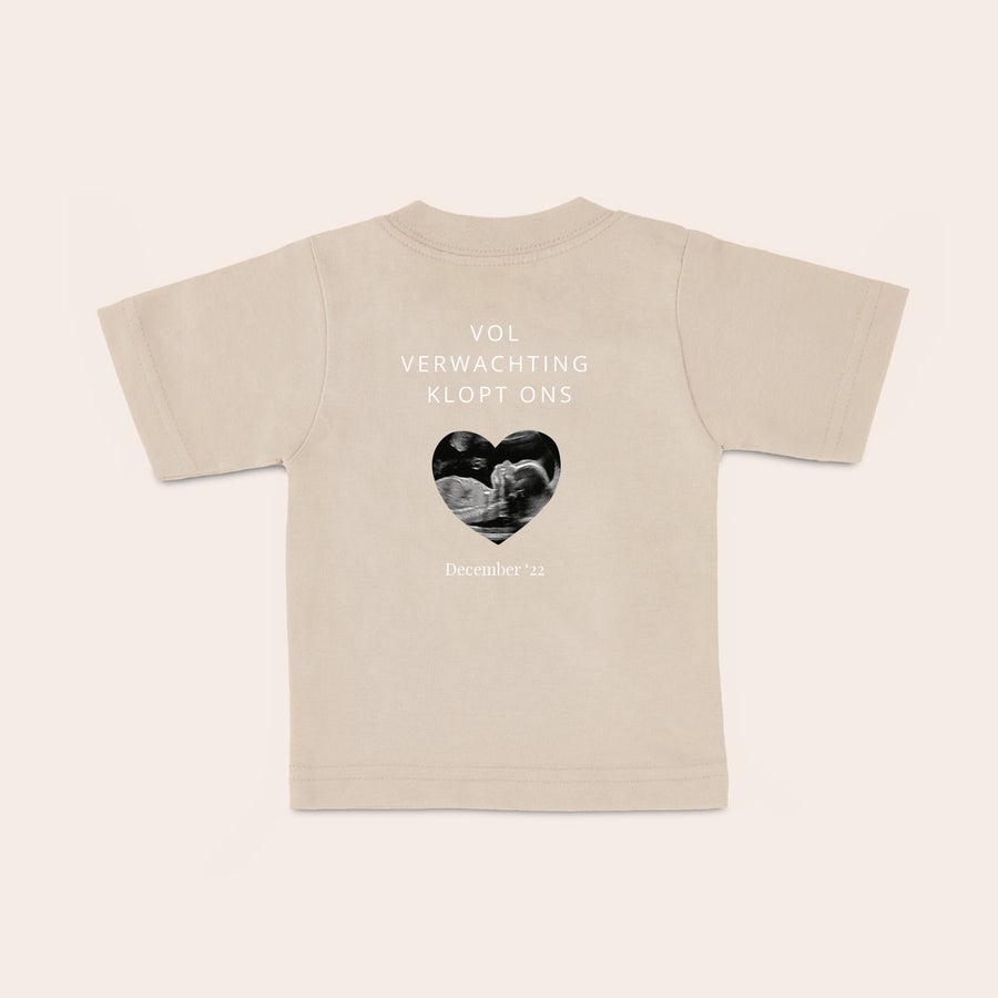 Baby shirt bedrukken Bèbeige baby shirt met naam in een hartvorm, bedrukt met echofoto en de tekst 'VOL VERWACHTING KLOPT ONS' en 'December '22'.