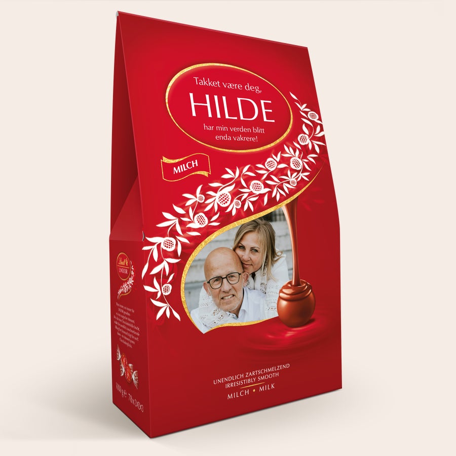 Lindt gaveeske med 1 kg sjokolade Rød Lindor sjokoladegaveeske med personlig trykt bilde av et par og tekst "HILDE" og "Takket være deg, har min verden blitt enda vakrere!"