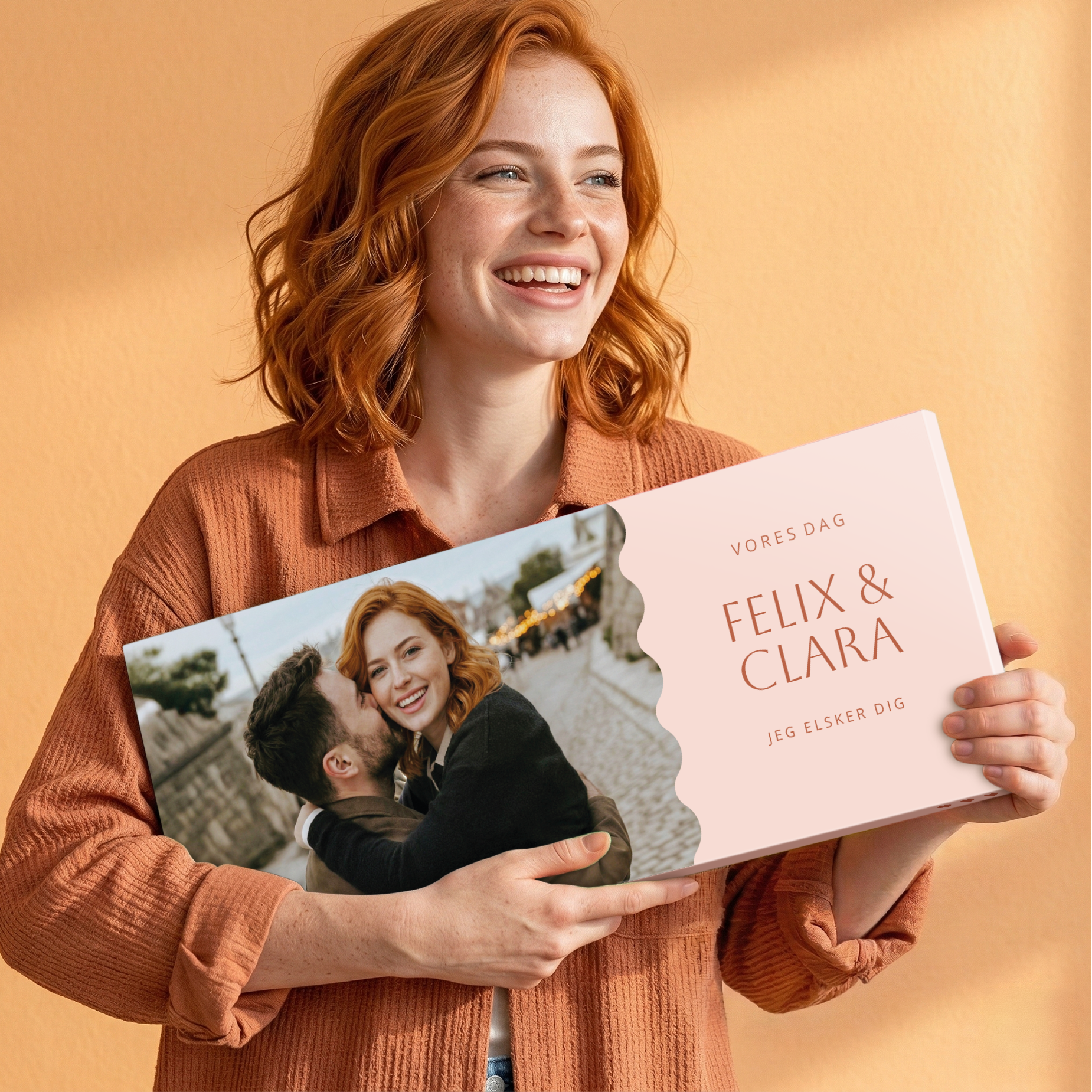 En smilende kvinde holder en Personaliseret Mega chokoladebar - Ritter Sport - 8 barer. Chokoladebaren er trykt med et billede af et par og teksten "Vores dag, Felix & Clara, Jeg elsker dig".