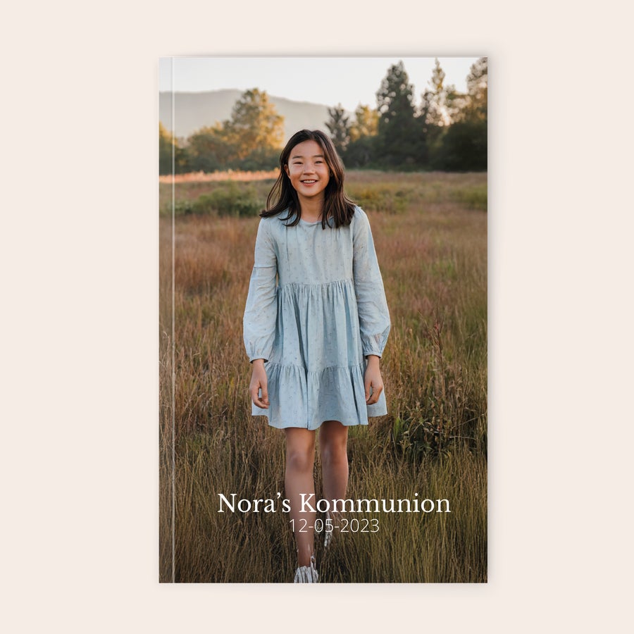 Notizbuch bedrucken Personalisiertes Notizbuch mit dem Foto eines lächelnden Mädchens in einem Feld, bedruckt mit "Nora's Kommunion 12-05-2023"