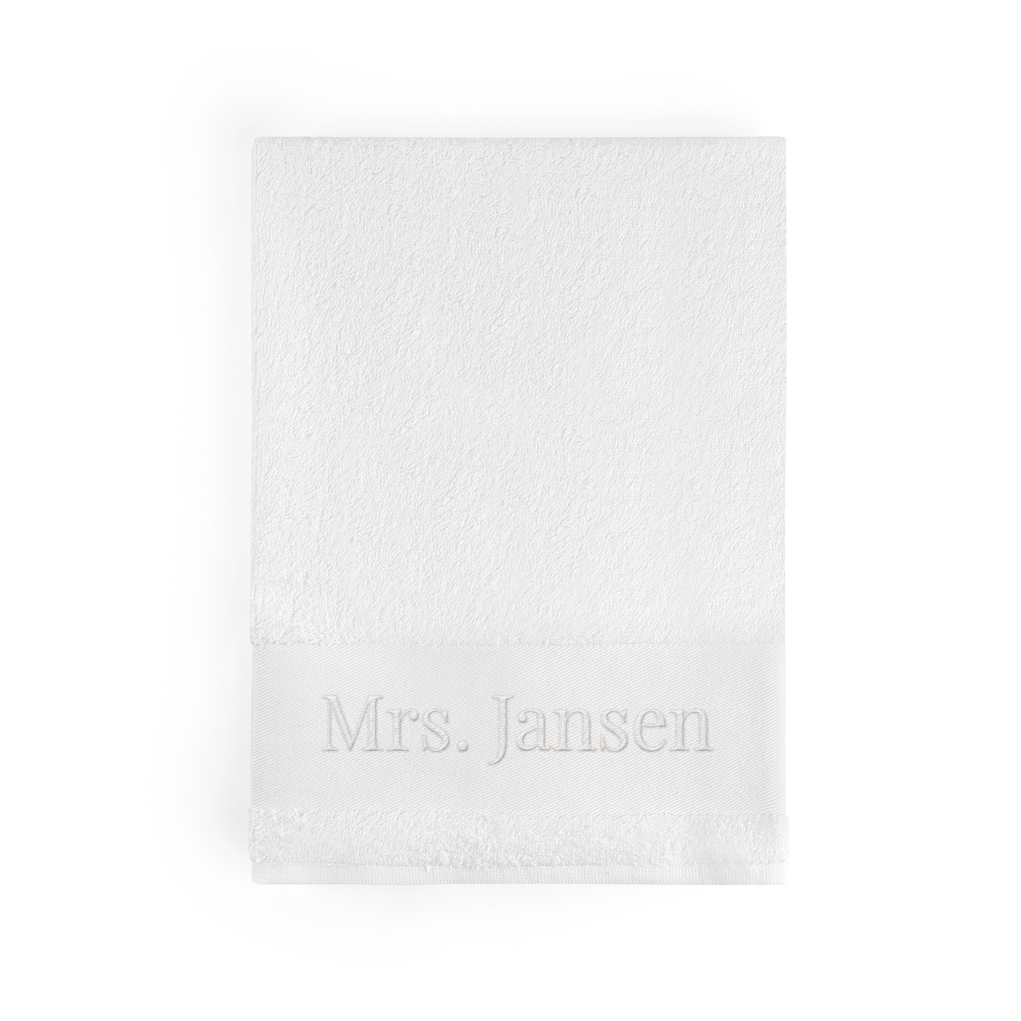 Witte handdoek met naam 'Mrs. Jansen' geborduurd in lichtgrijs op de rand, om iemand mee te verrassen.