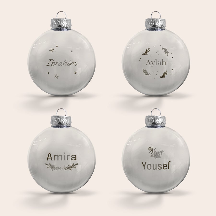 Boule de Noël Personnalisée en Verre Quatre boules de Noël en verre personnalisées et gravées avec des prénoms et des motifs décoratifs