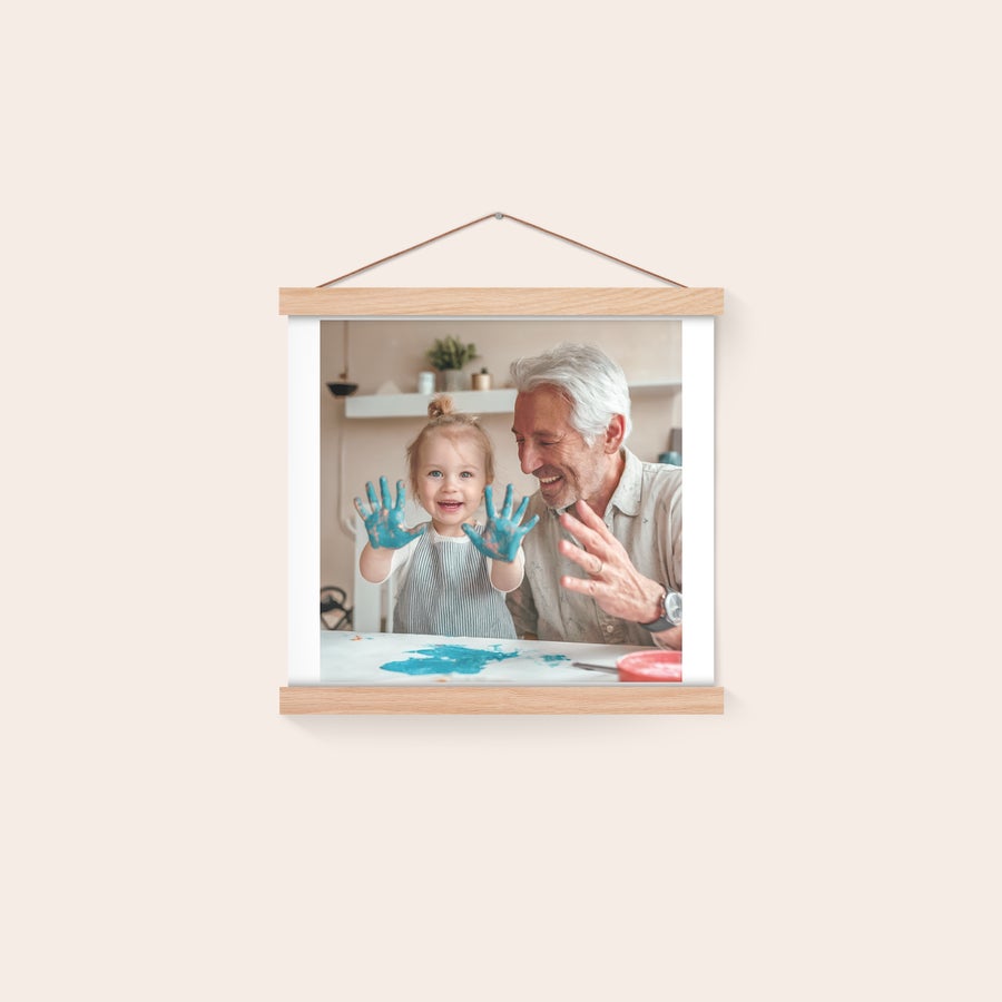 Personalised poster with hanger Personalized photo poster printed with a smiling child and an adult man painting, displayed in a magnetic poster hanger.