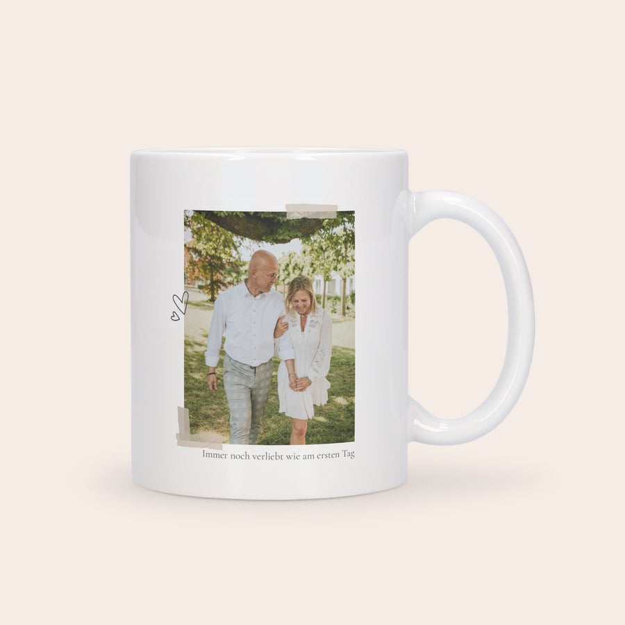 Tasse Liebe Eine personalisierte Tasse, bedruckt mit einem gemeinsamen Foto eines Paares und dem Text "Immer noch verliebt wie am ersten Tag". Eine personalisierte Tasse kann auch total romantisch sein.
