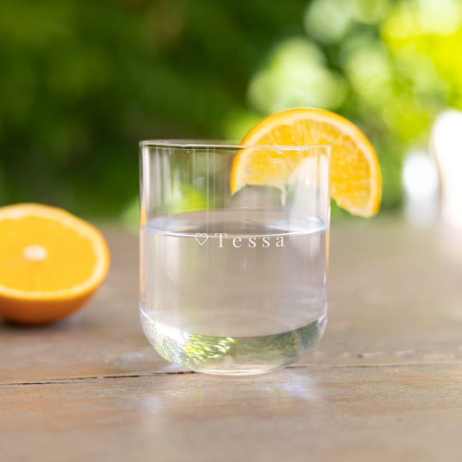 Vasos de agua personalizados Vaso de agua de cristal personalizado con el nombre "Tessa" grabado con láser y un corazón, con una rodaja de naranja.