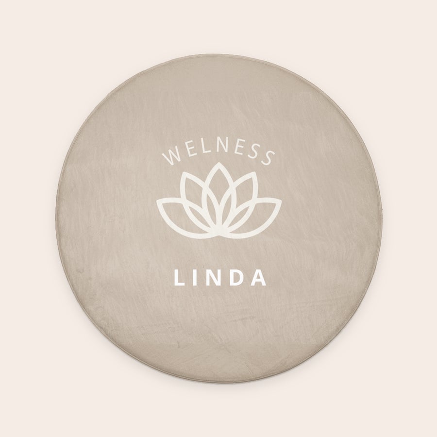 Ronde badmat bedrukken - ø 70 cm Ronde beige badmat, bedrukt met witte tekst "WELLNESS LINDA" en lotusbloem, voor elke badkamer.