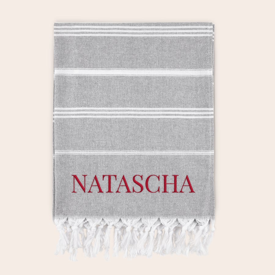 Hamamtuch personalisiert Graues Hamamtuch mit weißen Streifen, bestickt mit dem roten Namen NATASCHA, ideal für den Sommer