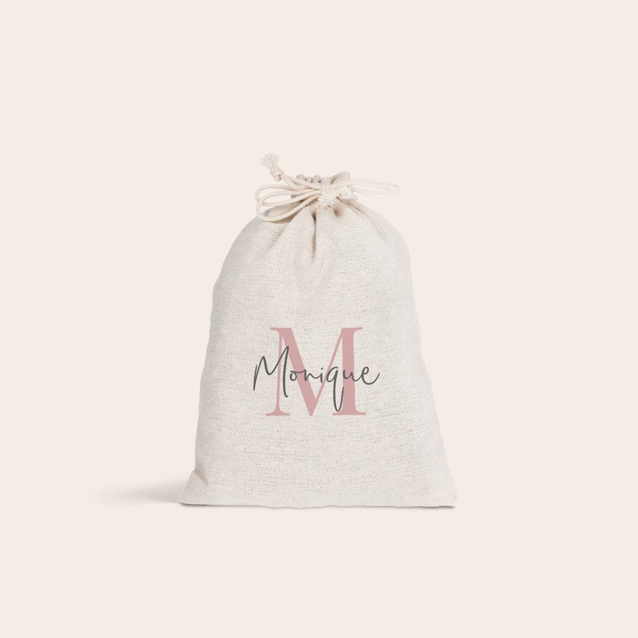Katoenen zakje Gepersonaliseerd katoenen zakje, bedrukt met een roze hoofdletter M en de naam Monique in sierlijke letters