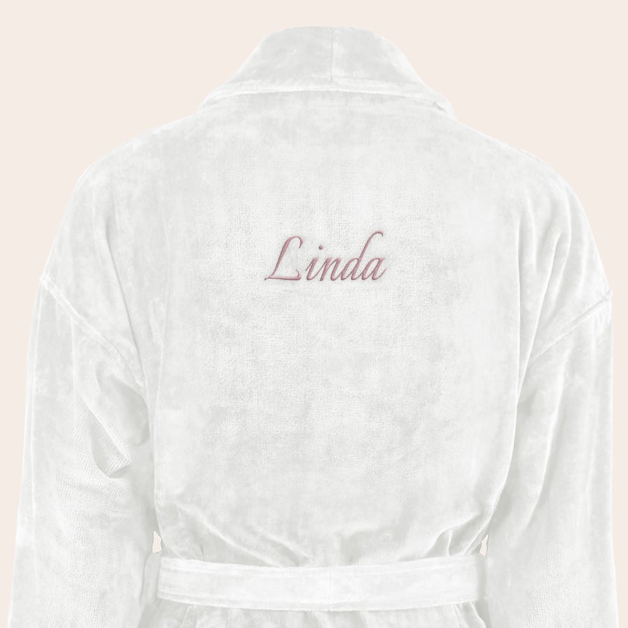 Badekåpe for kvinner med navn Hvit myk badekåpe brodert med navnet "Linda" i rosa skrift på ryggen.