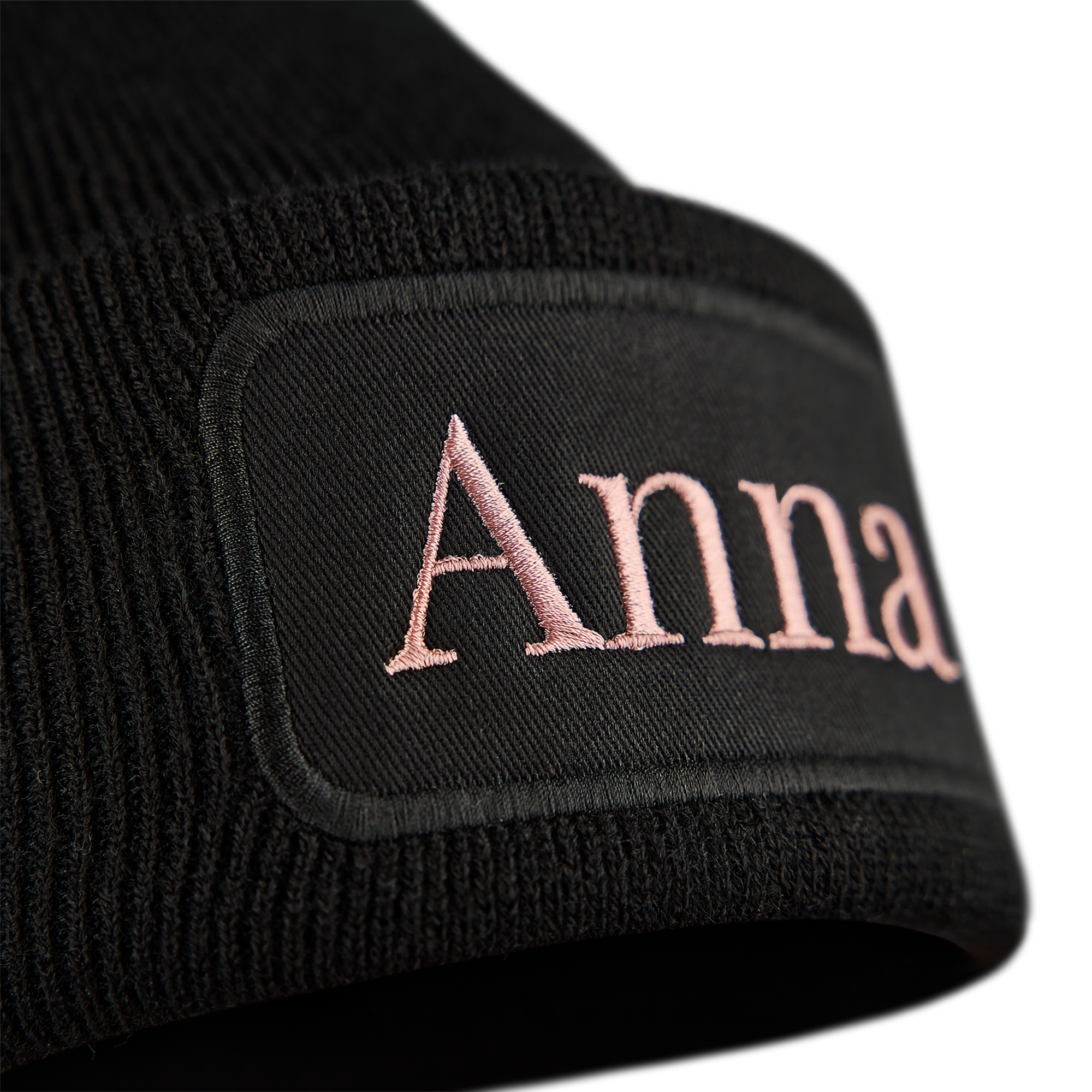 Sort beanie med broderet navn Anna i rosa på en etiket foran for at holde ørerne varme.