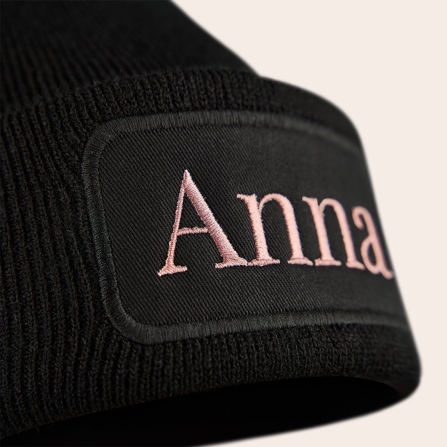 Pipo nimellä - Brodeeraus Musta pipo brodeerattuna vaaleanpunaisella tekstillä "Anna", johon voi personoida nimen