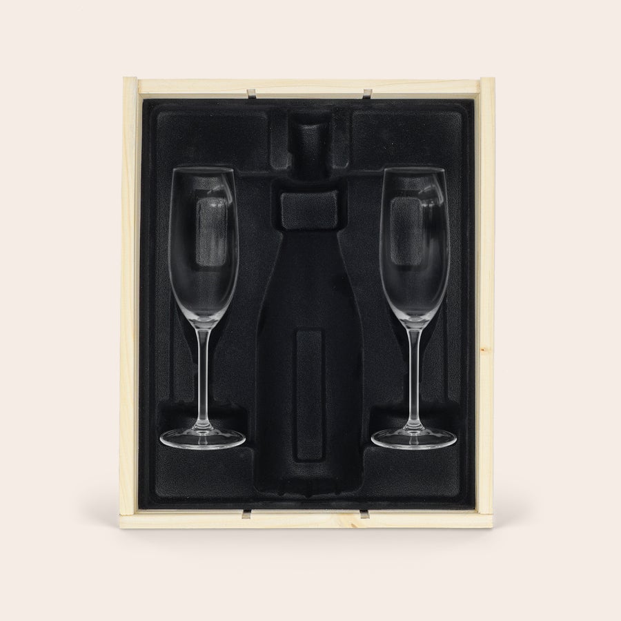 Personlig champagnelåda med glas Graverad champagne-ask i ljust trä med svart inlägg och två tomma champagneglas, med utrymme för en flaska.
