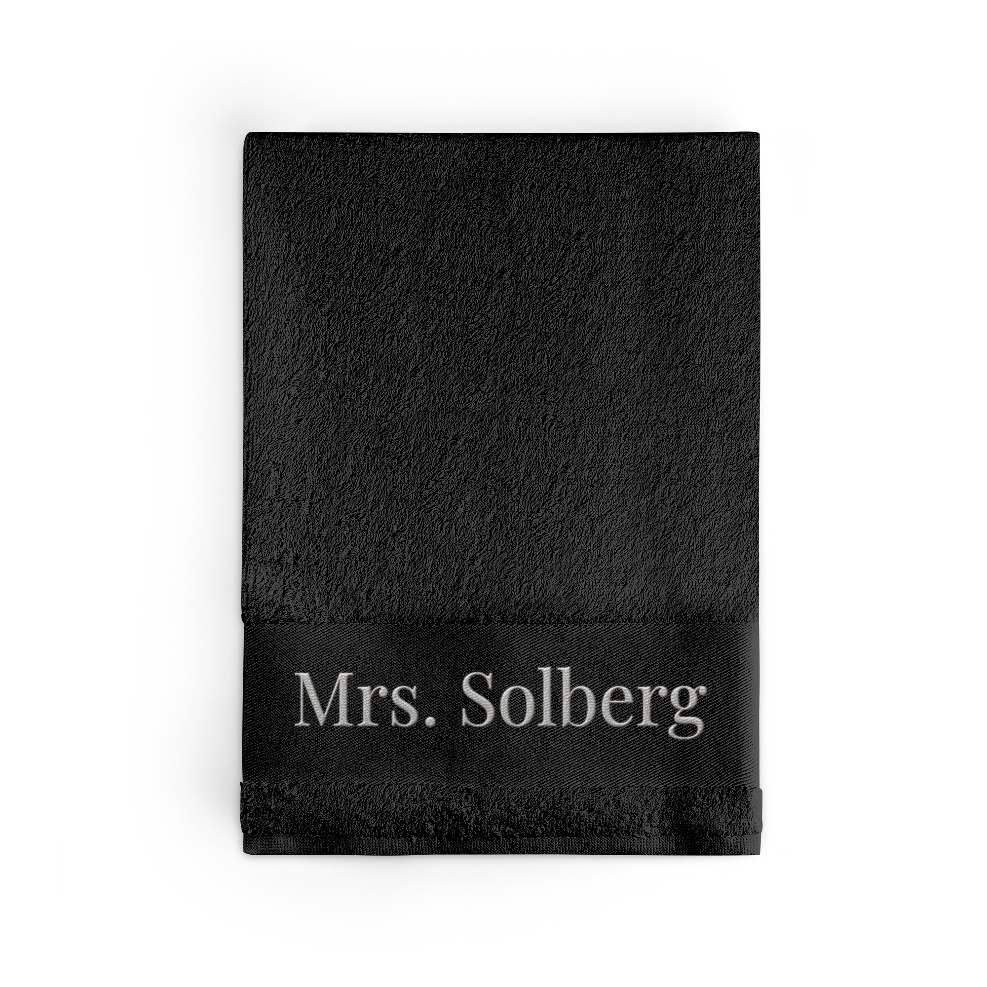 Svart brodert håndkle med navnet Mrs. Solberg i sølvtråd.