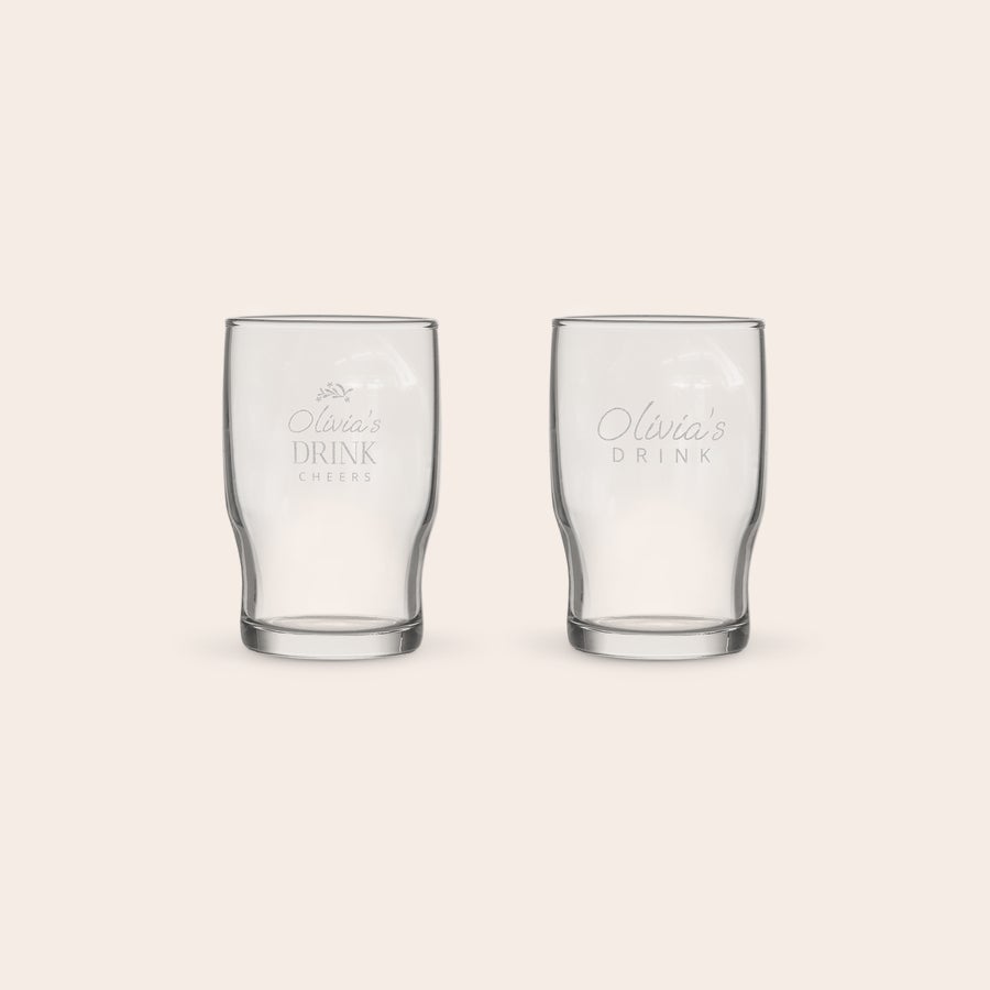 Bicchieri Acqua Personalizzati Una coppia di bicchieri d'acqua personalizzati incisi con il testo "Olivia's Drink Cheers" e un motivo floreale.