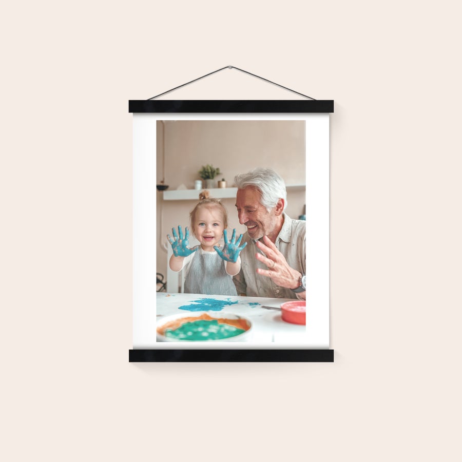 Personalised poster with hanger Personalized photo poster printed with a picture of a baby and an adult man, hanging from a magnetic poster hanger