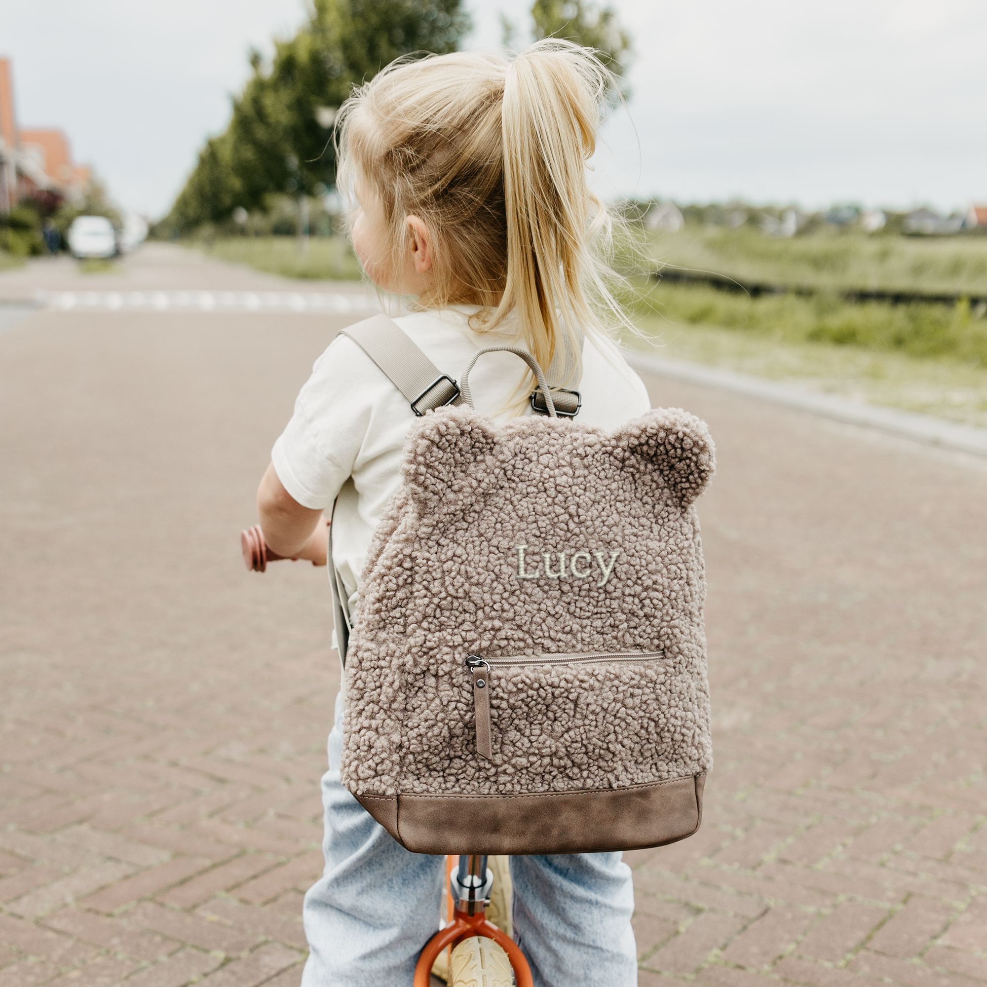Enfant avec un sac a dos en moumoute personnalise et brode du nom Lucy, rayonnez de bonheur avec un sac a dos en moumoute.