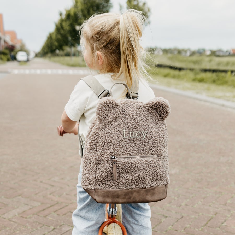 Zaino orsacchiotto personalizzato Zaino teddy personalizzato marrone chiaro con nome Lucy ricamato, indossato da una bambina bionda