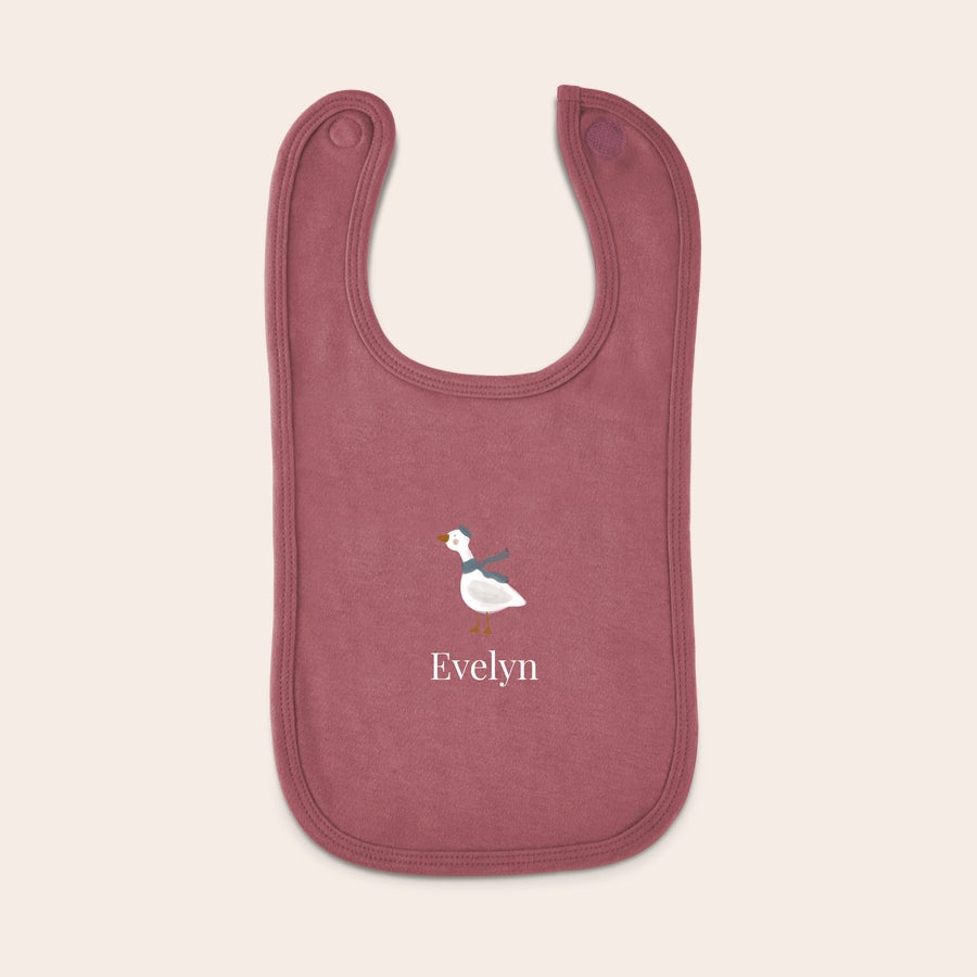 Personalised baby bib Personalised bib in dusty pink with a printed goose wearing a blue hat and scarf and the name Evelyn