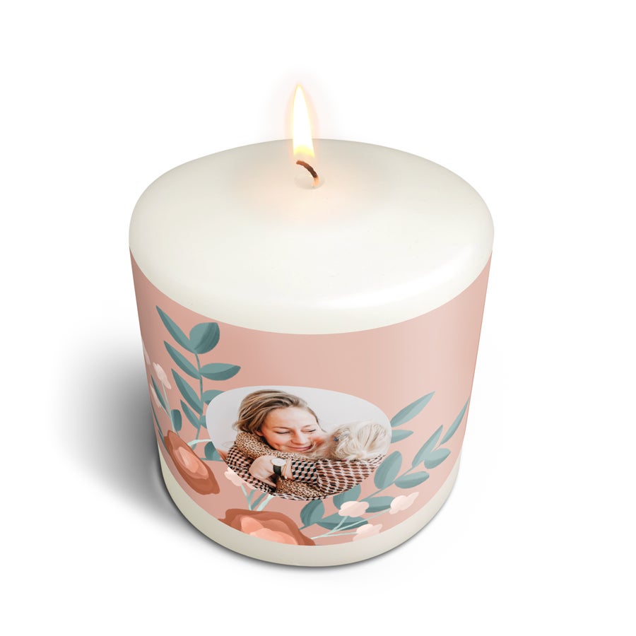 Kerze bedrucken mit Foto - 9x10 cm Weiße Kerze mit brennender Flamme, bedruckt mit einem persönlichen Foto einer Frau, die ein Baby umarmt, umgeben von einem Blumenmuster.