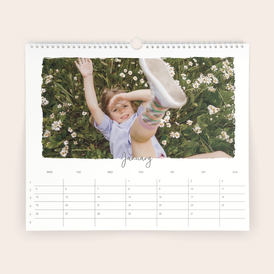 Årskalender 2026 Personlig årskalender med tryckt eget foto av ett barn som ligger i gräset bland vita blommor