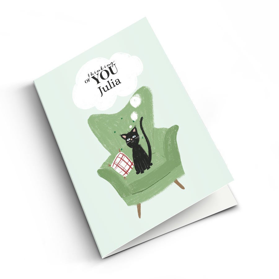 Személyre szabott fényképes kártya fekete macskával egy fotelban, "thinking of YOU Julia" felirattal, nyomtatással.